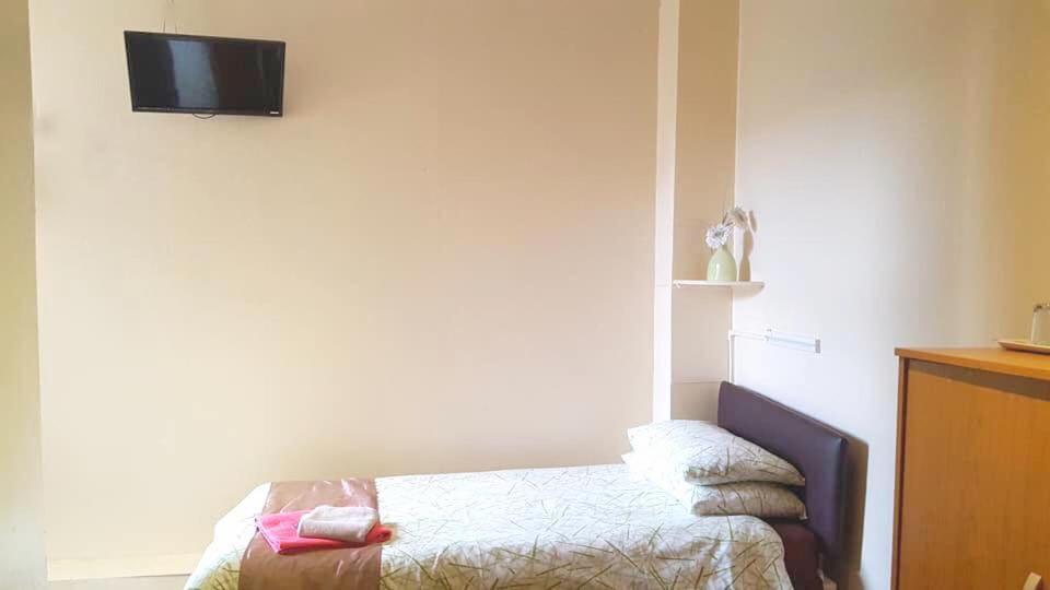 a bedroom with a bed and a tv on the wall at Tudor Rose Hotel in Blackpool