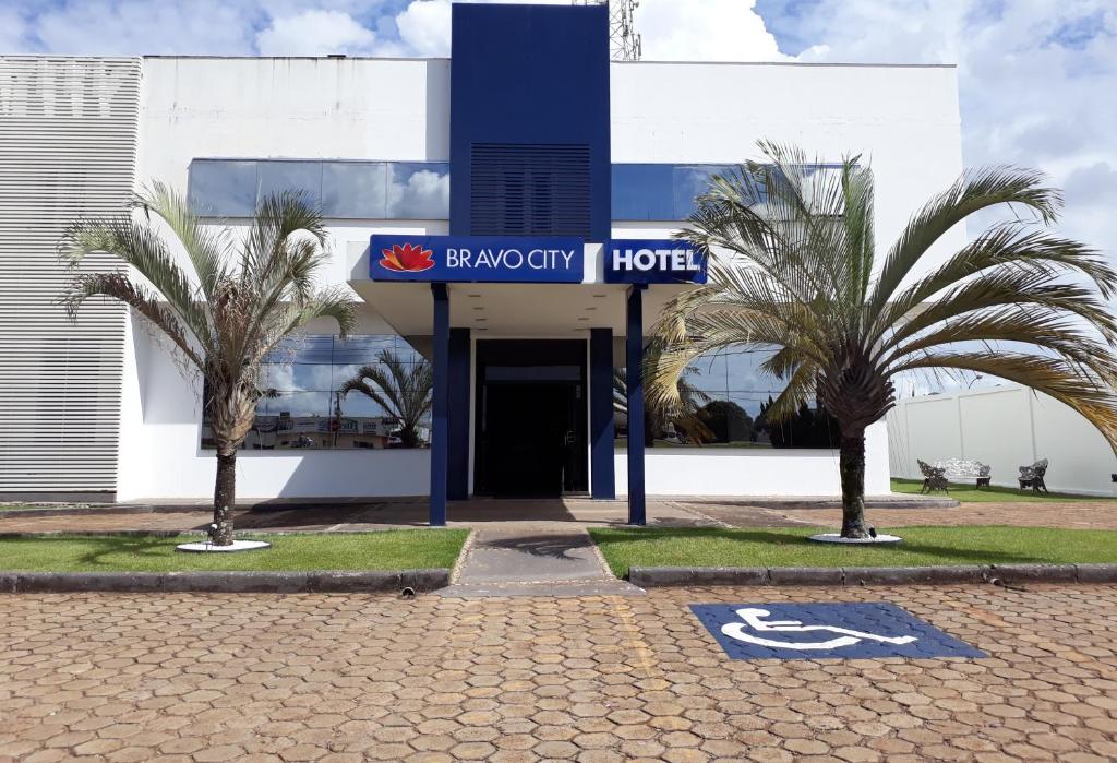 a hotel with palm trees in front of a building at Bravo City Hotel Primavera in Primavera do Leste