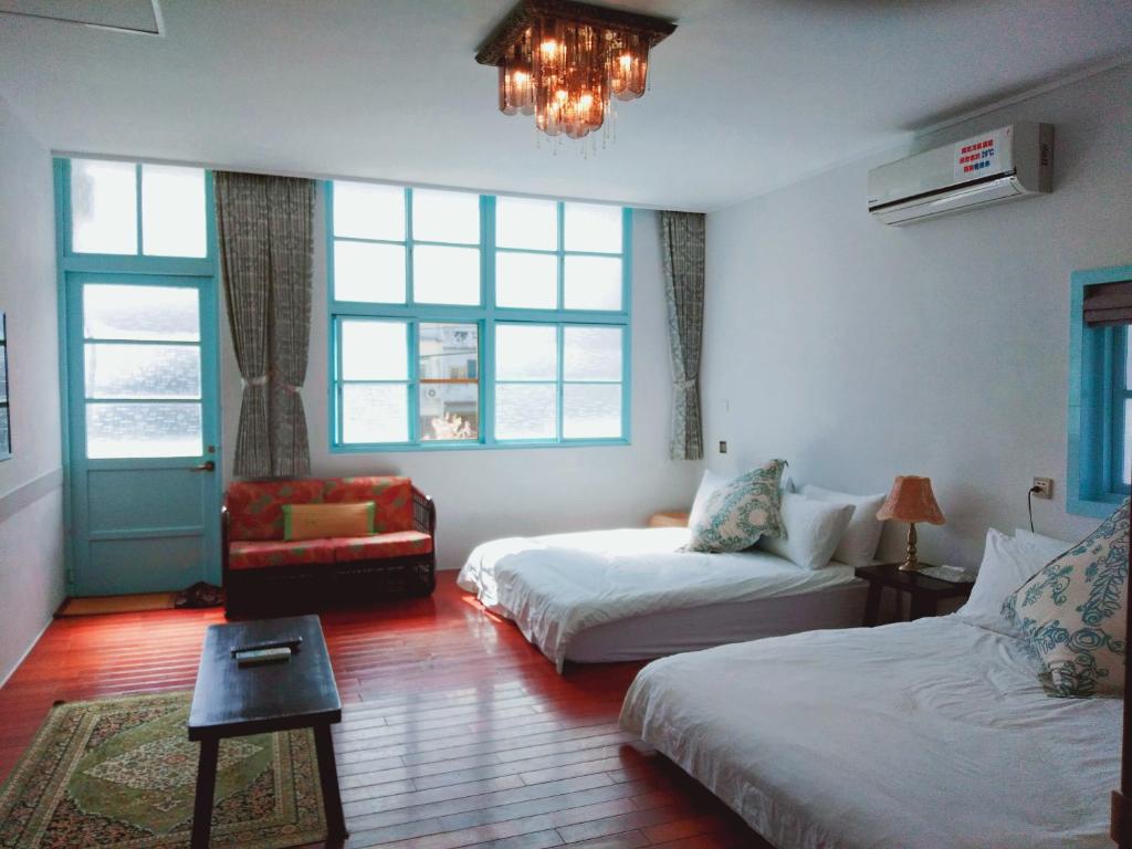 1 dormitorio con 2 camas, silla y lámpara de araña en 小時公館, en Yuli