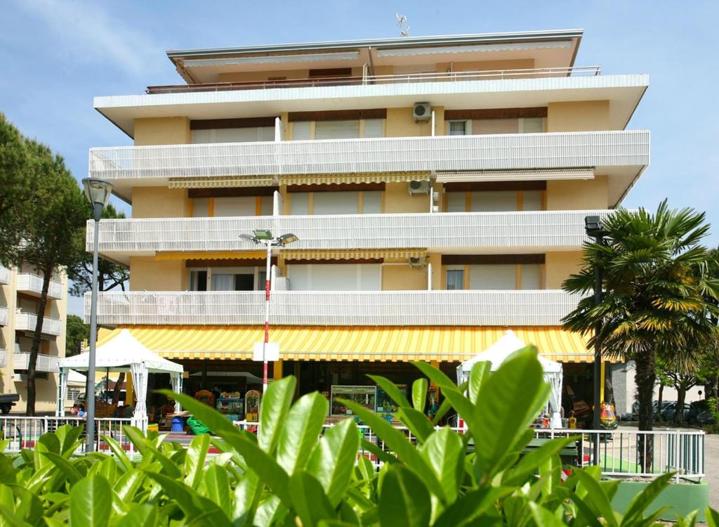 un edificio alto de color amarillo con balcón blanco en Apartments in Bibione 24550, en Bibione