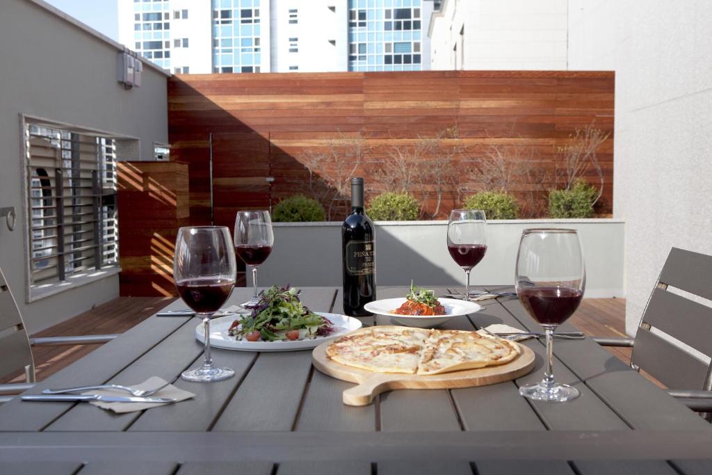 a table with wine glasses and a pizza and salad at S Stay Hotel Dongtan in Hwaseong