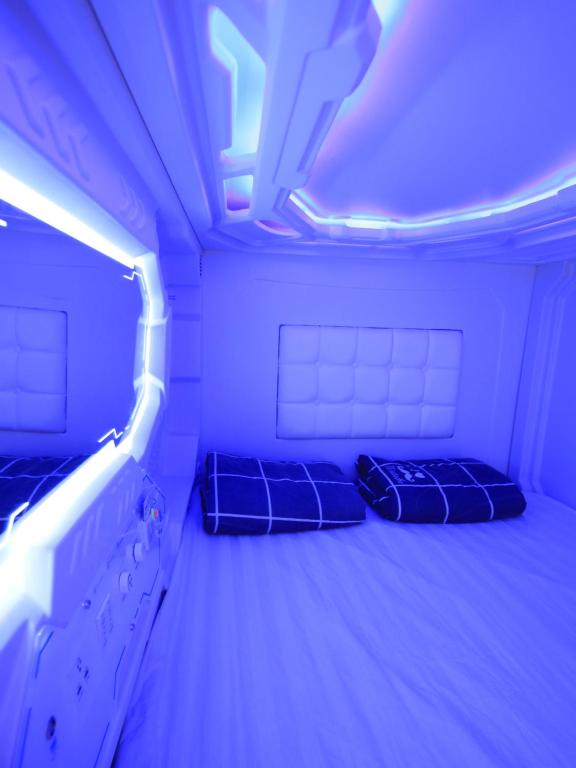 2 łóżka w pokoju z fioletowymi światłami w obiekcie Spacepod@hive w Singapurze