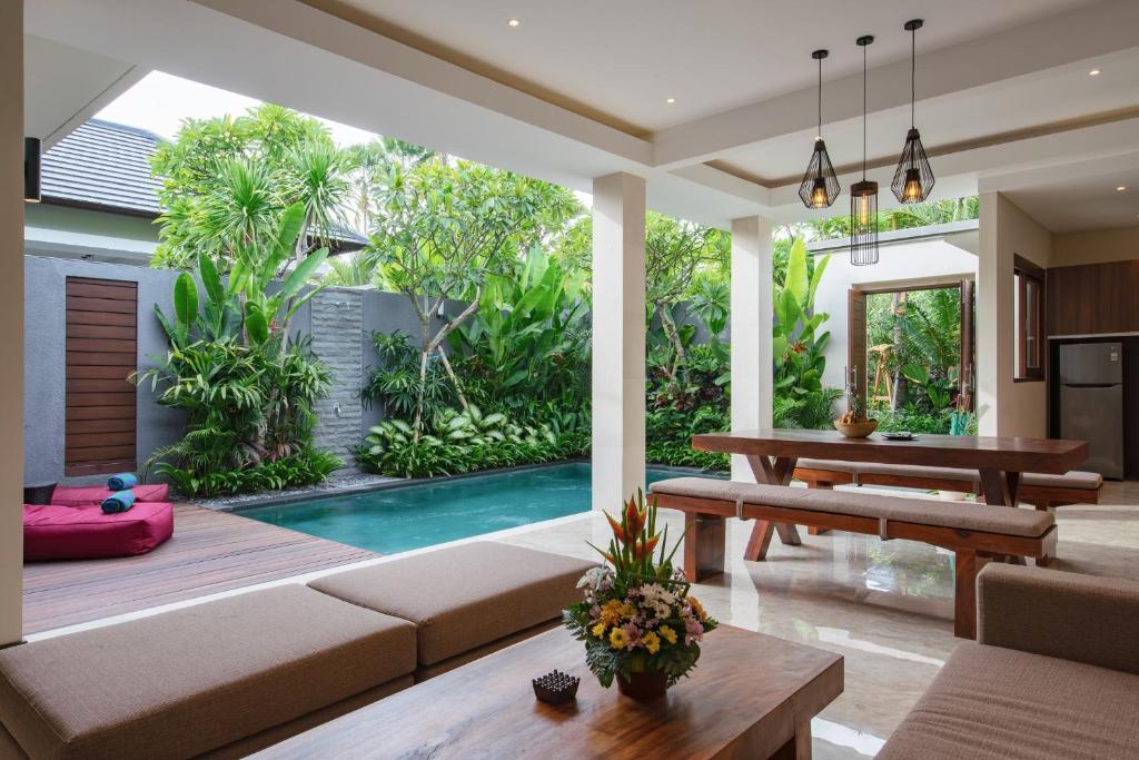 an open living room with a pool and a table at Villa Sally in Canggu