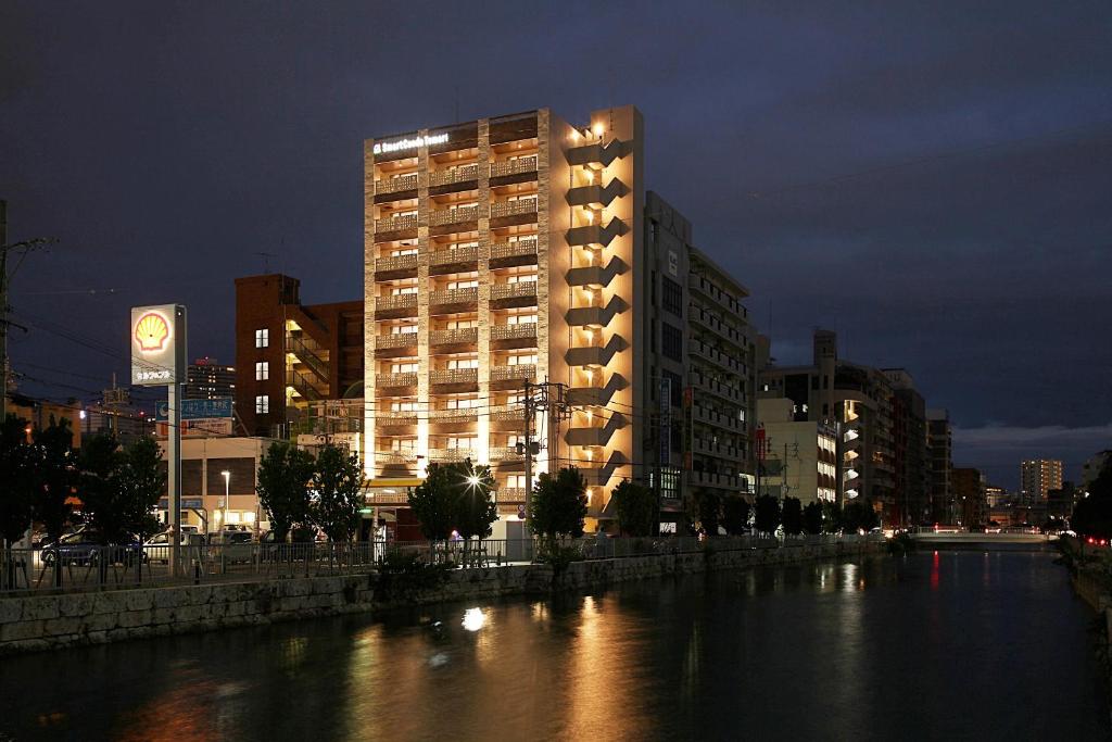 un gran edificio en una ciudad con un río por la noche en Smart Condo Tomari en Naha
