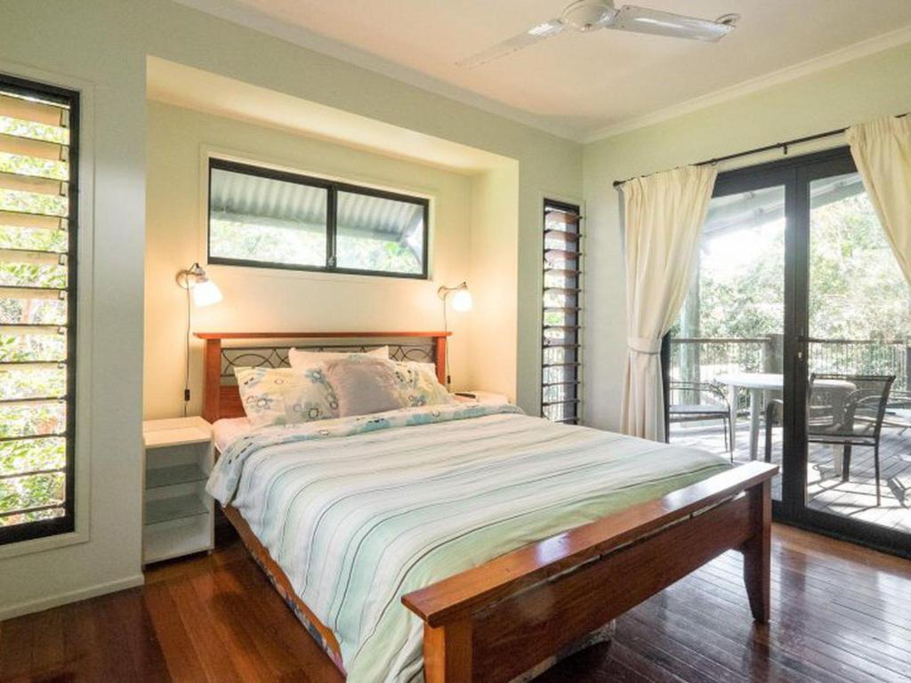 a bedroom with a bed and a balcony with a table at Billa Blue in Point Lookout