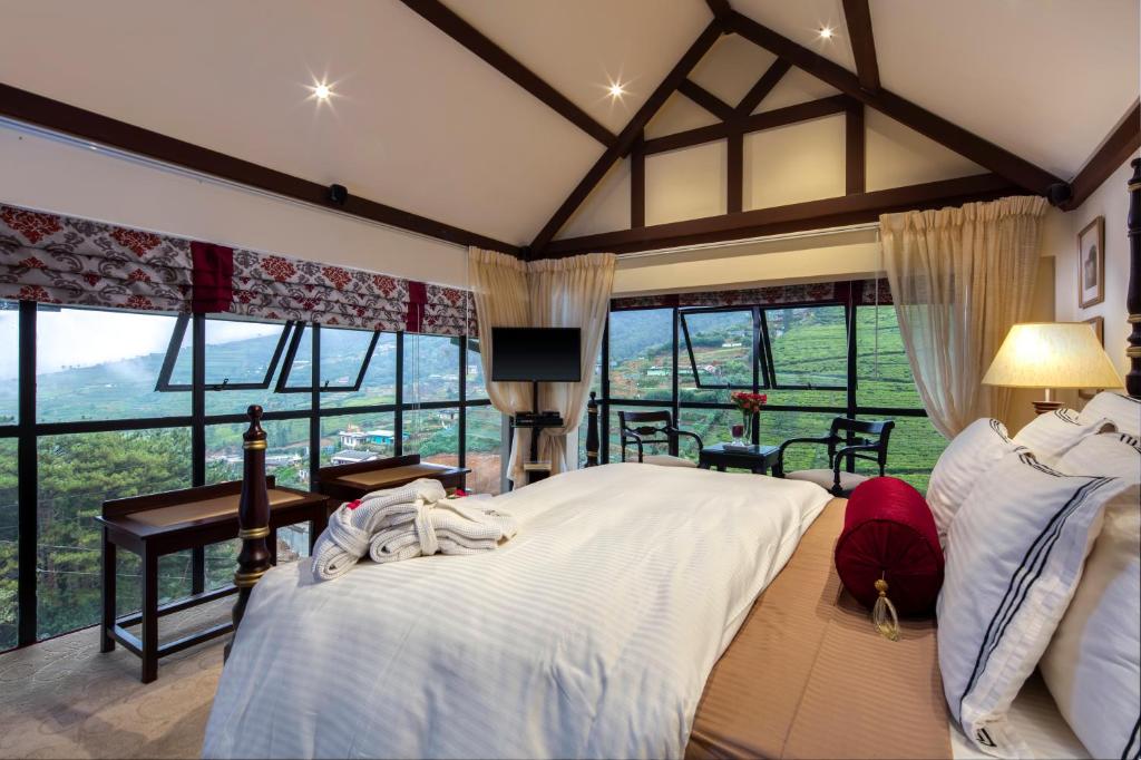 a bedroom with a large bed and large windows at CheRiz Boutique Villa Hotel in Nuwara Eliya