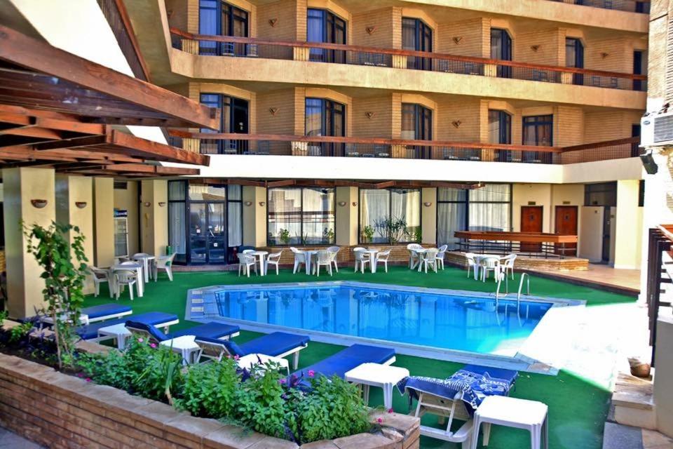 a hotel with a swimming pool with chairs and tables at Gaddis Hotel, Suites and Apartments in Luxor