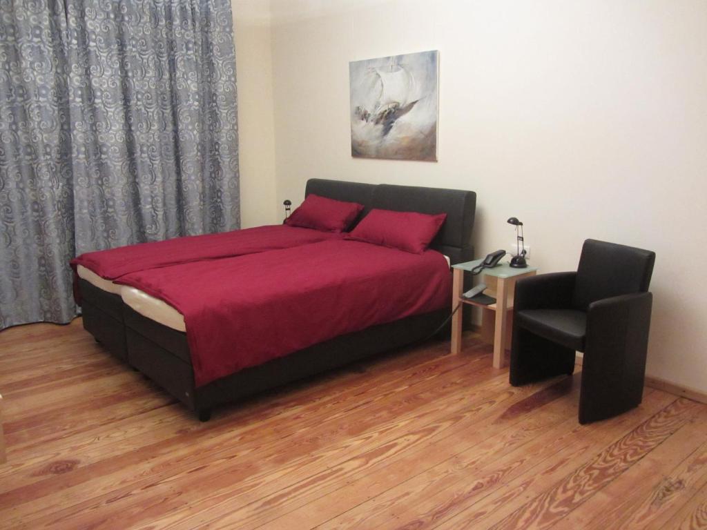 ein Schlafzimmer mit einem Bett mit einer roten Decke und einem Stuhl in der Unterkunft Exklusive Gästezimmer Landau in Landau in der Pfalz