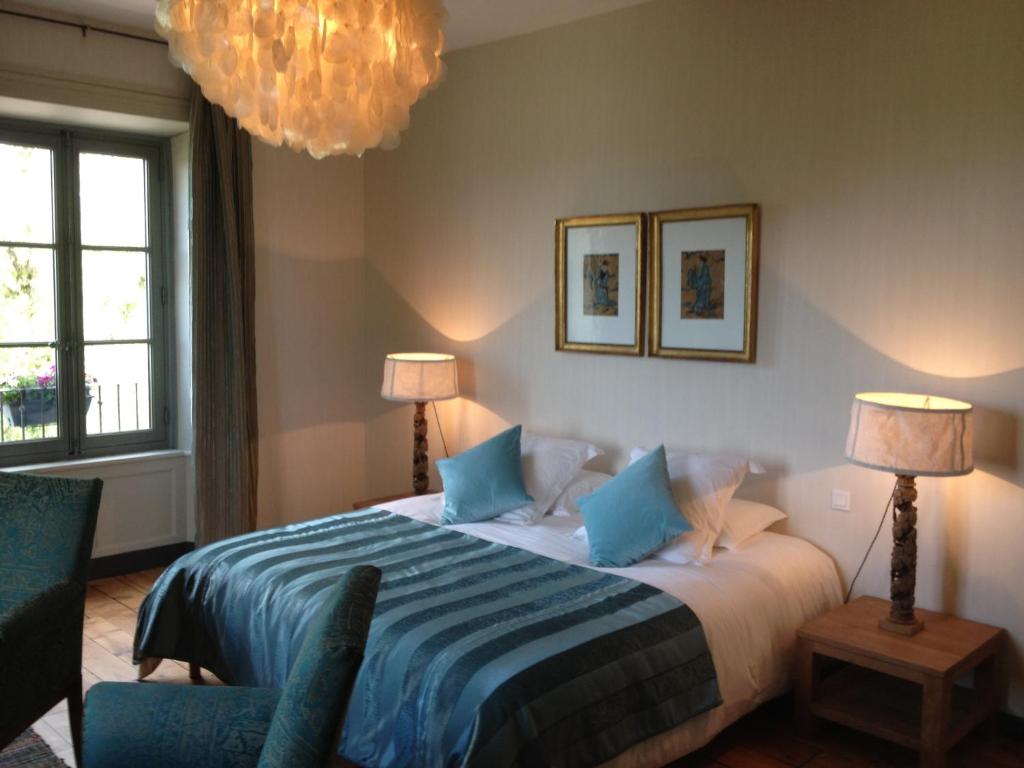ein Schlafzimmer mit einem Bett, einem Stuhl und einem Kronleuchter in der Unterkunft Le Rézinet - Chambres d'Hôtes in Marcilly le Chatel