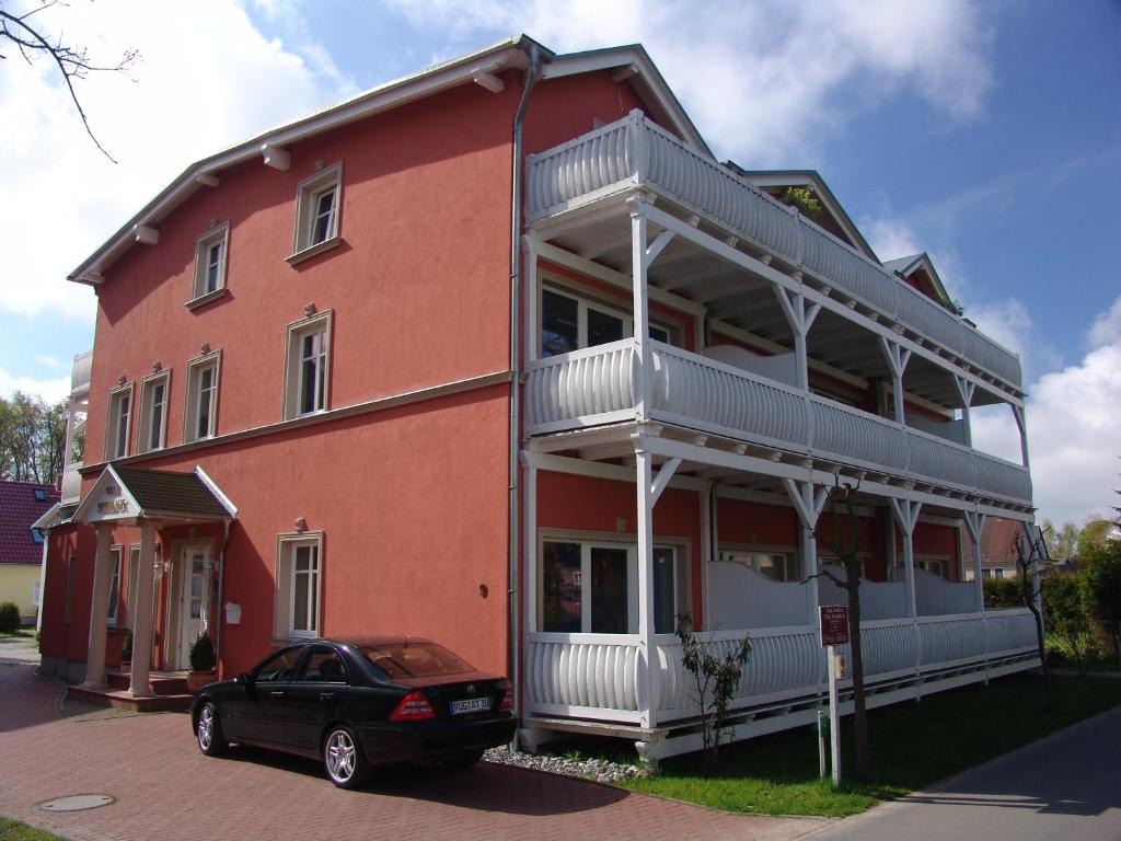 a black car parked in front of a red building at Apartments Villa Seeblick in Baabe