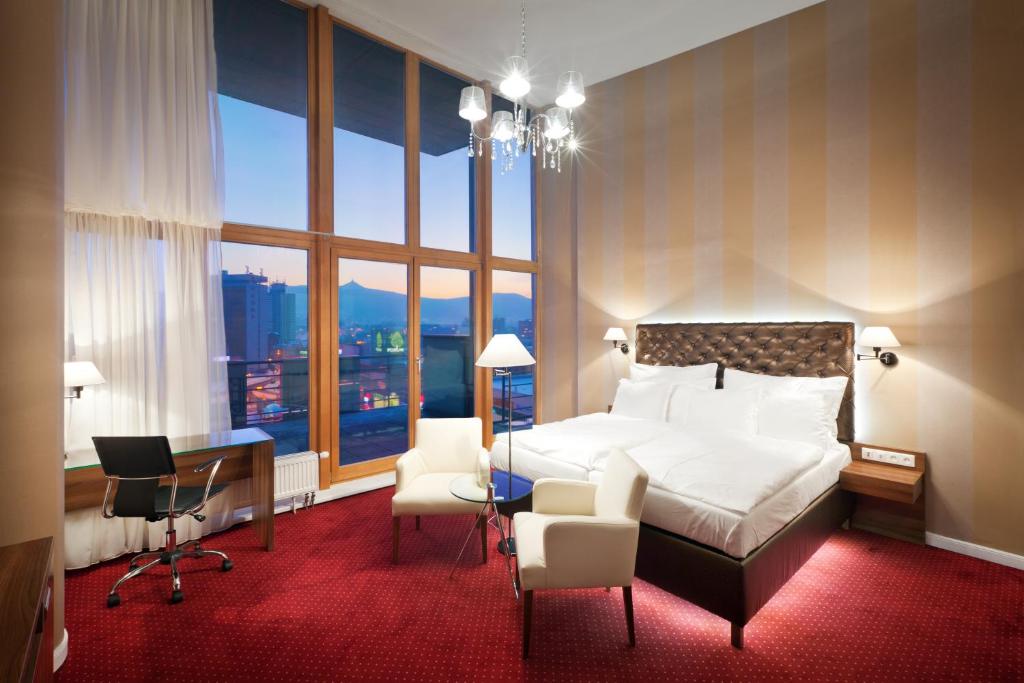 Habitación de hotel con cama, escritorio y ventanas en Pytloun City Boutique Hotel en Liberec