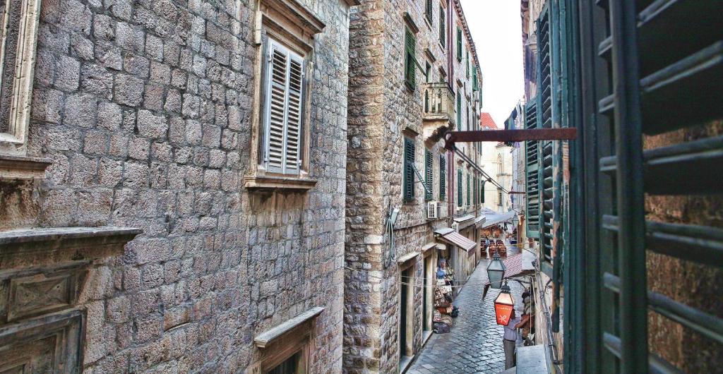 a narrow alley between two buildings with people walking down it at Kaboga street Rooms in Dubrovnik