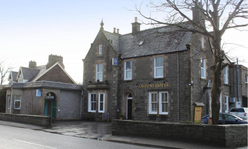 an old brick building on the side of a street at Queens hotel in Wick