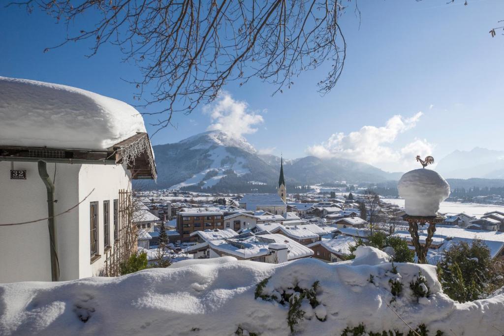 una ciudad cubierta de nieve con una montaña en el fondo en Ferienchalet Panoramablick, en Kössen