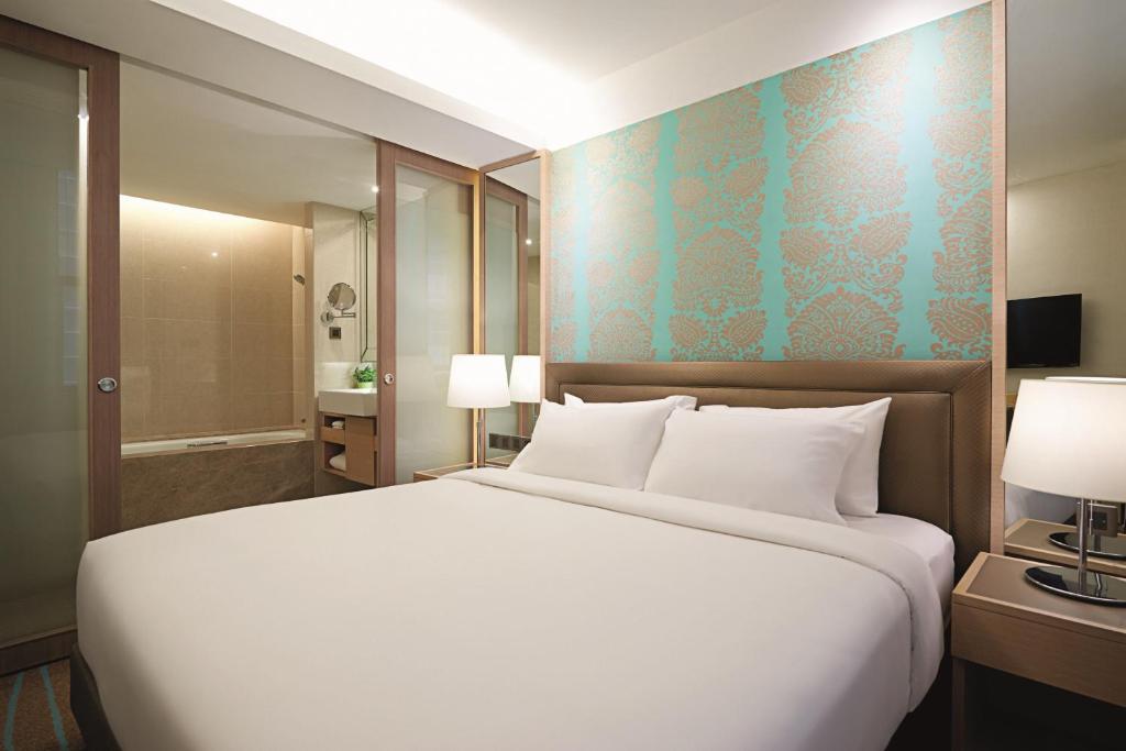 1 dormitorio con 1 cama blanca grande y baño en Cosmo Hotel Kuala Lumpur, en Kuala Lumpur