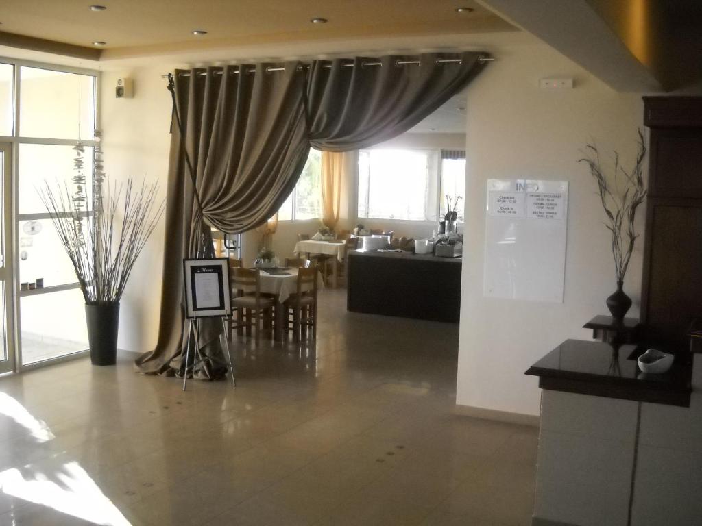 a living room with a curtain and a dining room at Thea Hotel in Possidi