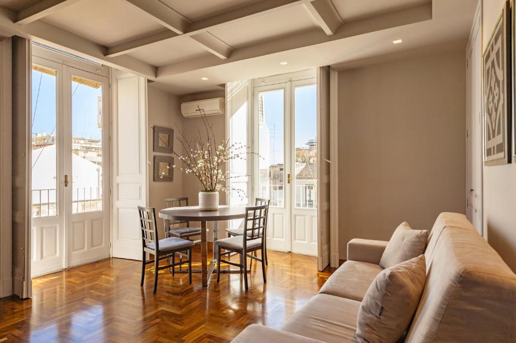 uma sala de estar com um sofá, uma mesa e cadeiras em Ferrini Home - Residence 150 em Catânia