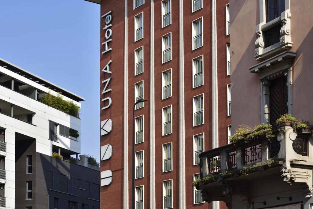 een gebouw van rode baksteen met een balkon ervoor bij UNAHOTELS Mediterraneo Milano in Milaan