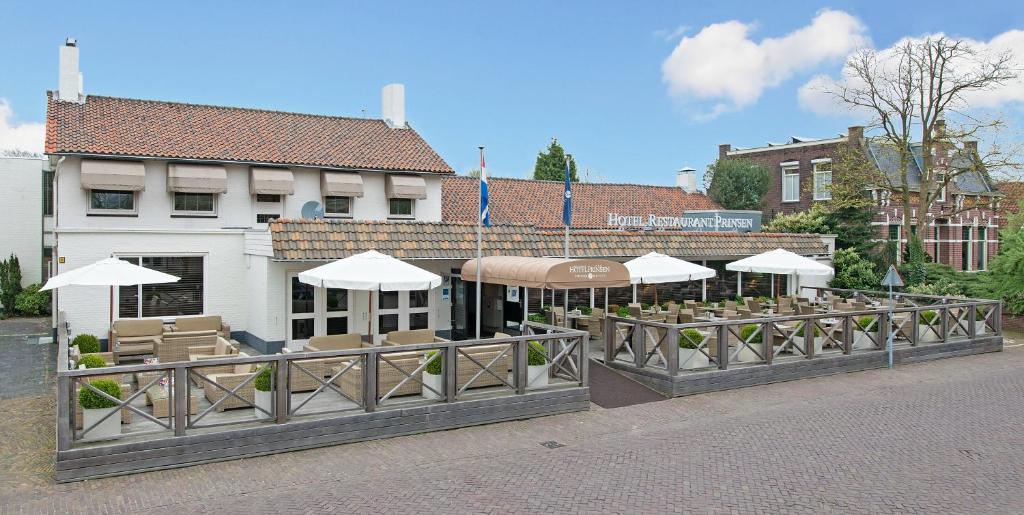 un restaurant avec des tables et des parasols en face d'un bâtiment dans l'établissement Fletcher Hotel Restaurant Prinsen, à Vlijmen