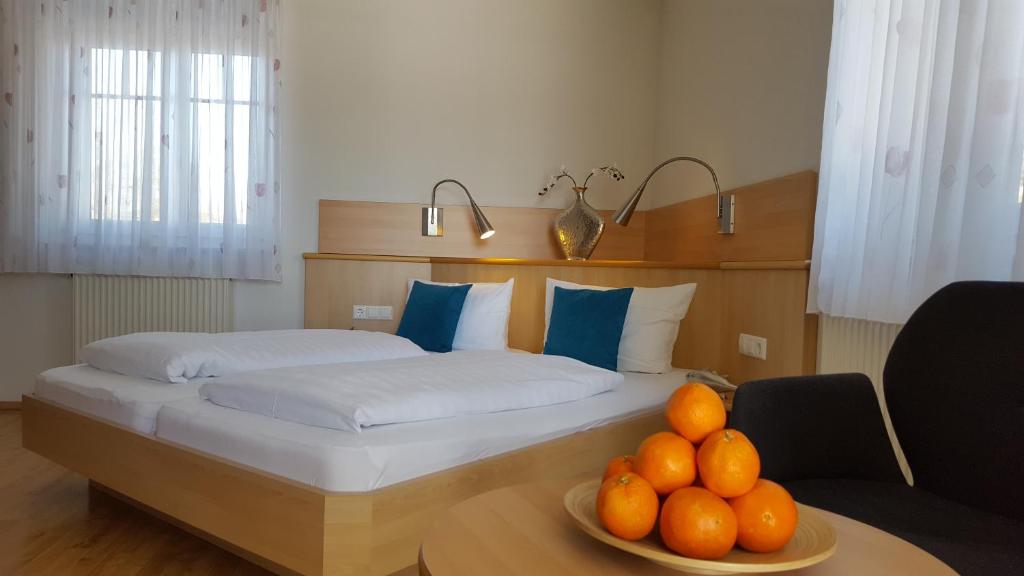 1 dormitorio con 1 cama con un plato de naranjas sobre una mesa en Hotel & Restaurant Karpfen, en Illmensee