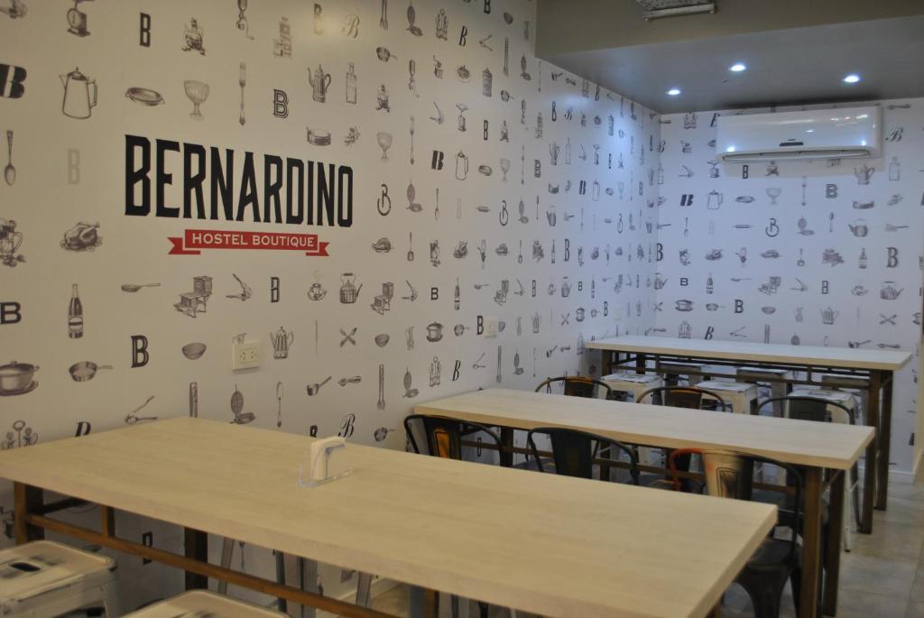 un comedor con mesas y una pared con escritura. en Bernardino Hostel Boutique en Neuquén