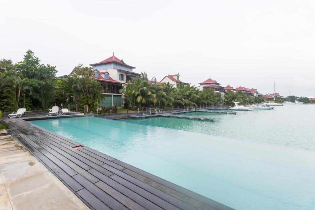 a large swimming pool next to a body of water at Eden Island Luxury One Bedroom Apartment in Mahe