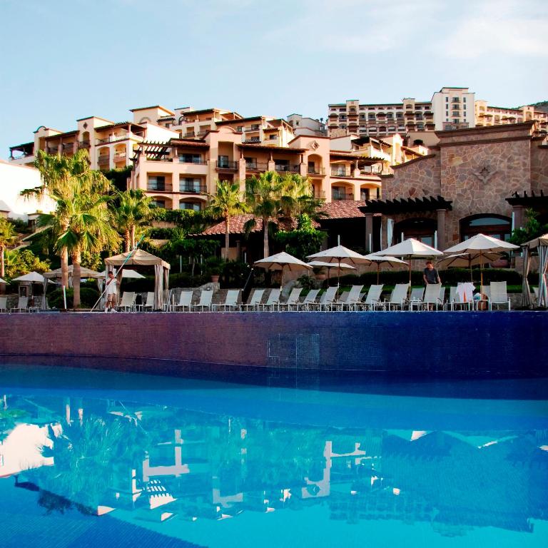 a swimming pool with chairs and umbrellas in a resort at Pueblo Bonito Sunset Beach Golf & Spa Resort - All Inclusive in Cabo San Lucas