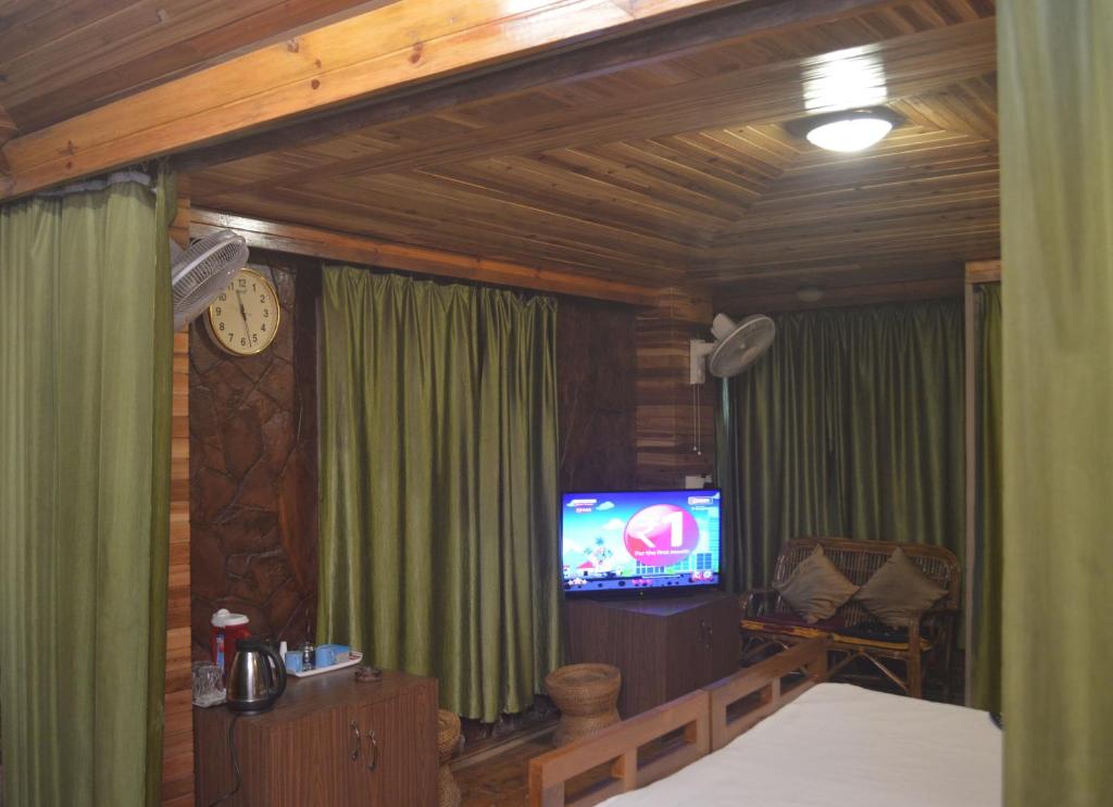 a room with a tv and a bed and a clock at Quinton Enclave in Shillong