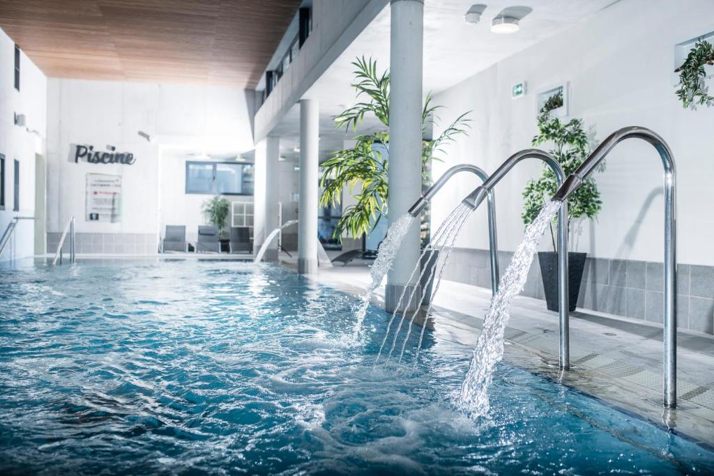 - une piscine avec des fontaines dans un bâtiment dans l'établissement Domaine Lou Capitelle & Spa, à Vogüé