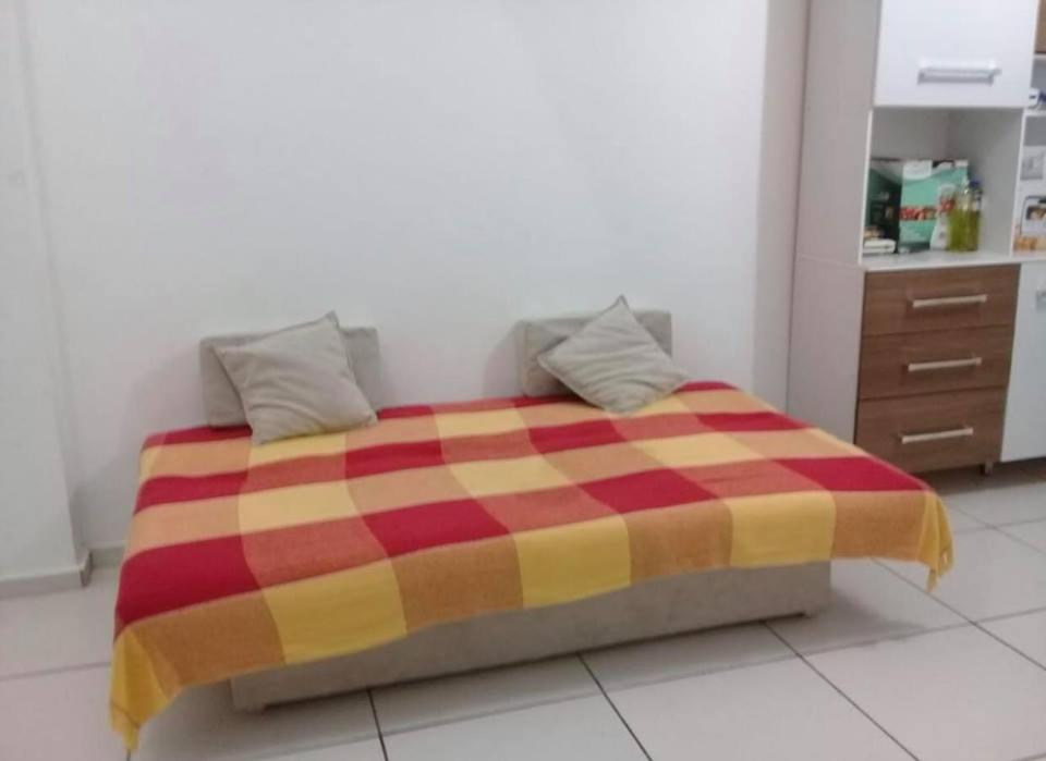 een bed in een kamer met een rode en gele deken bij Flat Shopping Amarração N - 129 in Luis Correia