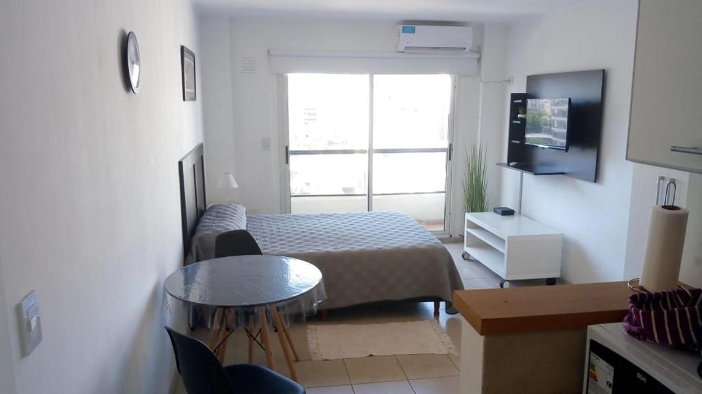 a bedroom with a bed and a table and a window at Monoambiente Barrio Martin in Rosario