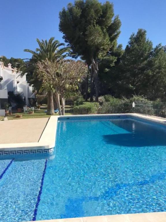 a blue swimming pool with trees in the background at Tranquil setting in Moraira