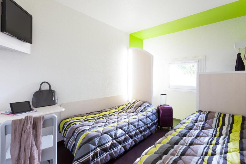 1 dormitorio con 2 camas y escritorio con TV en hotelF1 Besancon Ouest Micropolis en Besanzón