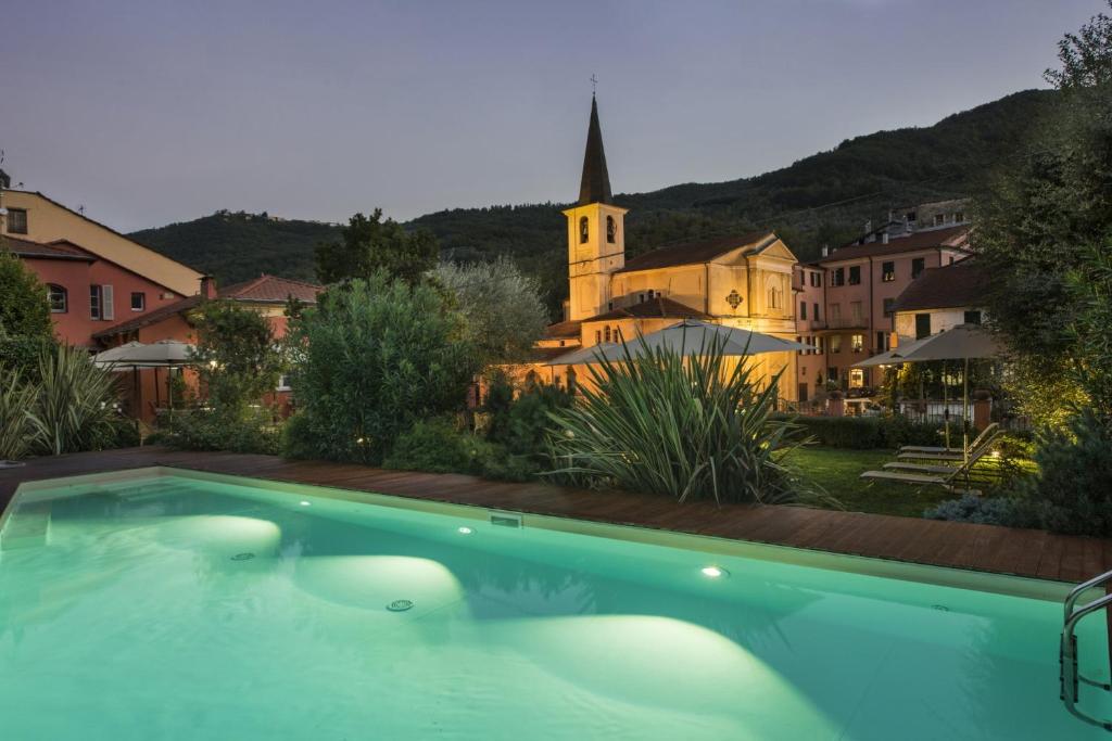 a swimming pool in front of a building with a church at Relais Del Maro in Borgomaro