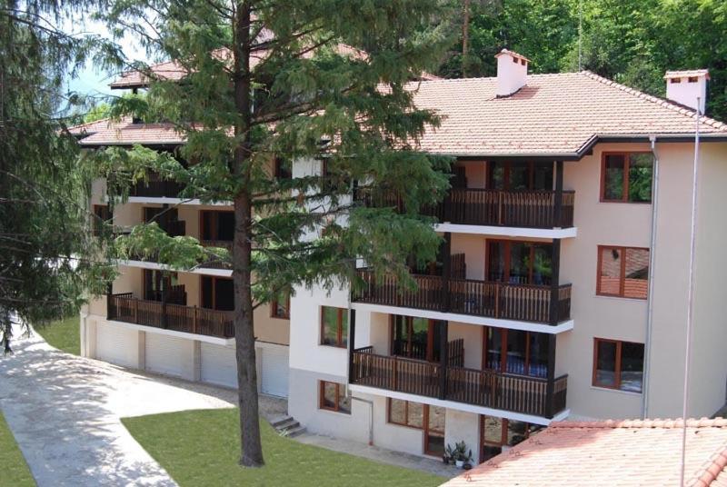 a white apartment building with balconies and a tree at Vidima Apartment Hotel in Apriltsi