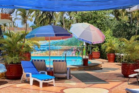 2 sillas y sombrillas junto a una piscina en Villas del Corazon - Iguana en Sayulita