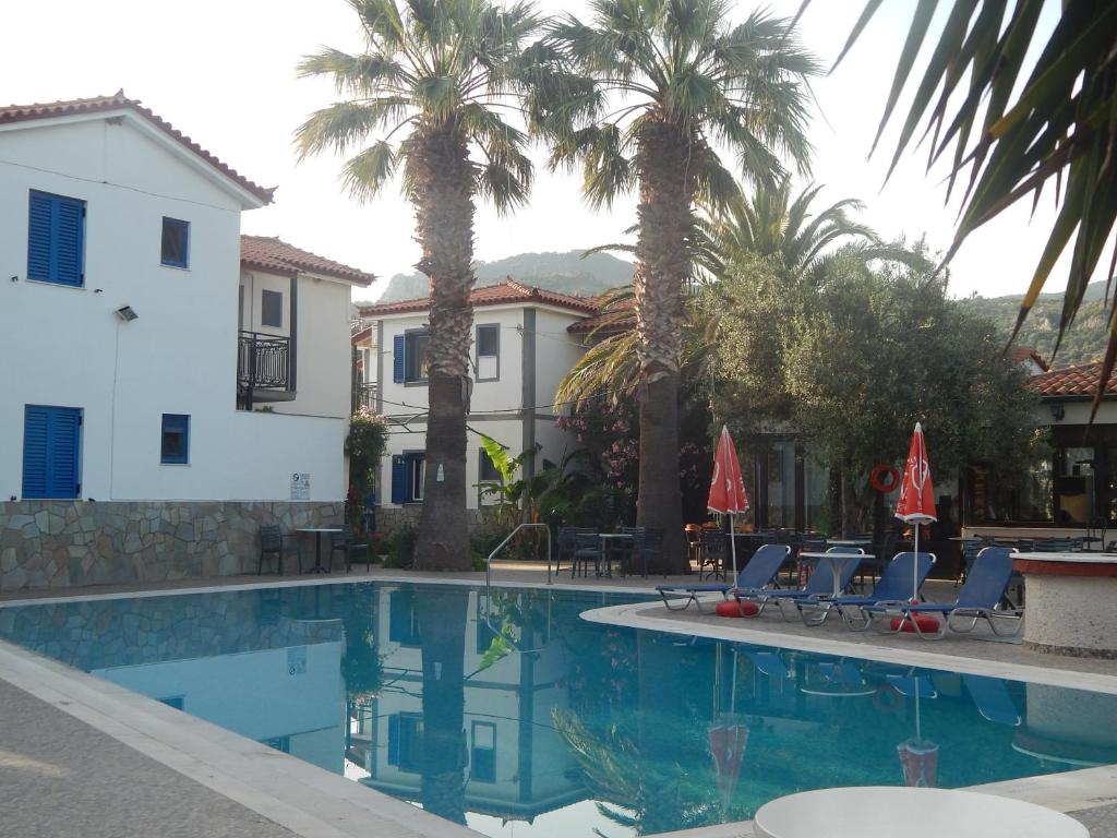 阿納索斯的住宿－Anaxos Gardens，一座带椅子和棕榈树的游泳池以及一座建筑