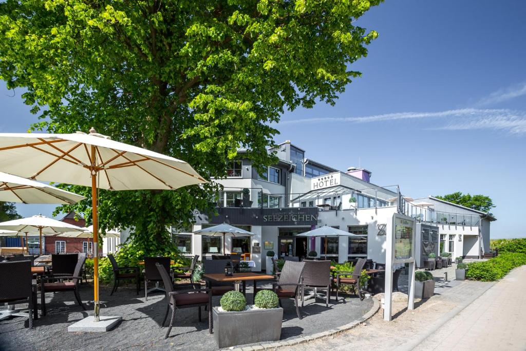 un restaurante con mesas, sillas y sombrilla en Hotel Seezeichen Ahrenshoop, en Ahrenshoop