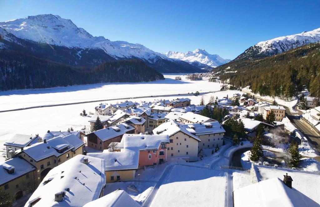 a village covered in snow with mountains in the background at Giardino Mountain in St. Moritz