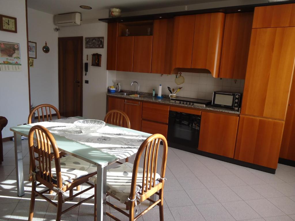 een keuken met een tafel en stoelen en een keuken met houten kasten bij La casa di Anna in Scorzè