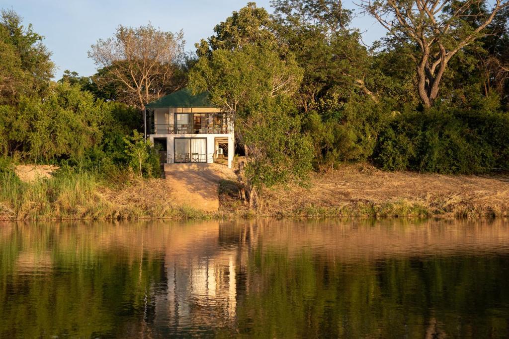 una casa en una colina junto a un cuerpo de agua en Kayube Boat House, en Livingstone