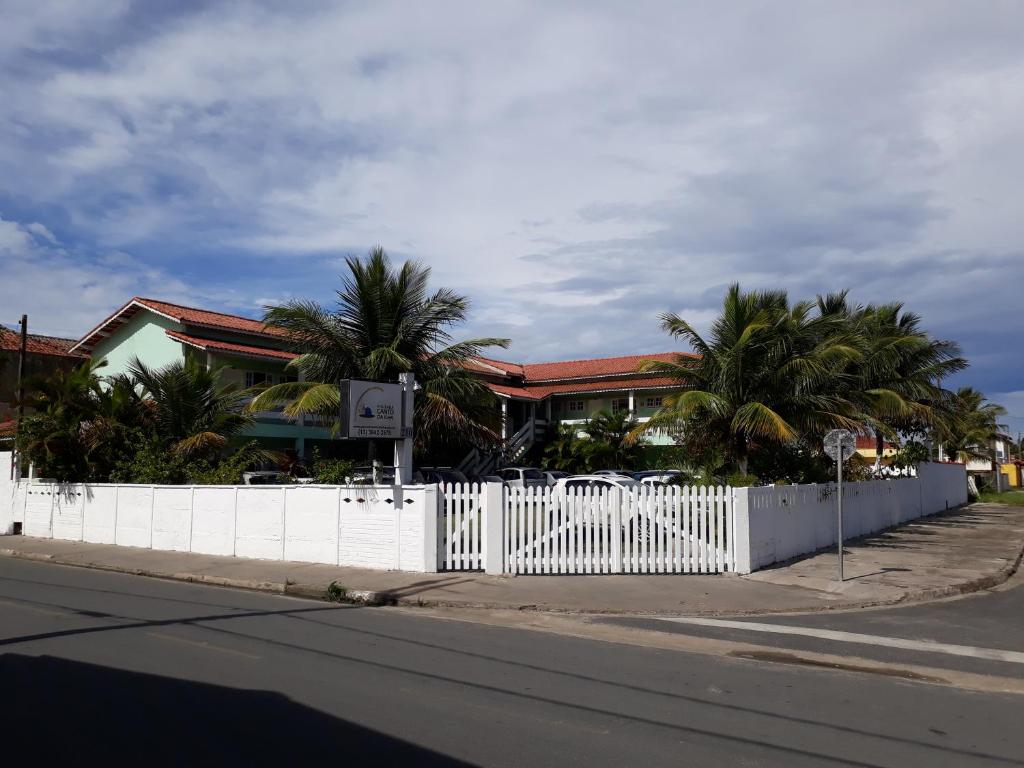 uma cerca branca em frente a um edifício com palmeiras em Pousada Canto da Ilha em Ilha Comprida