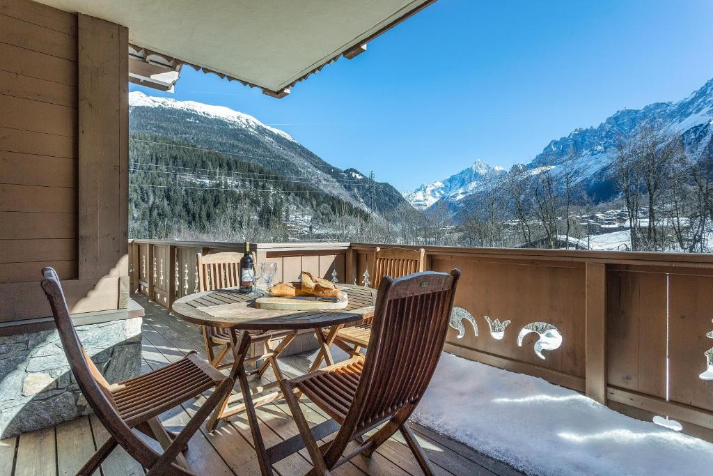 een tafel en stoelen op een balkon met uitzicht op de bergen bij APARTMENT KANDAHAR - Alpes Travel - Central Chamonix - Sleeps 4 in Les Houches