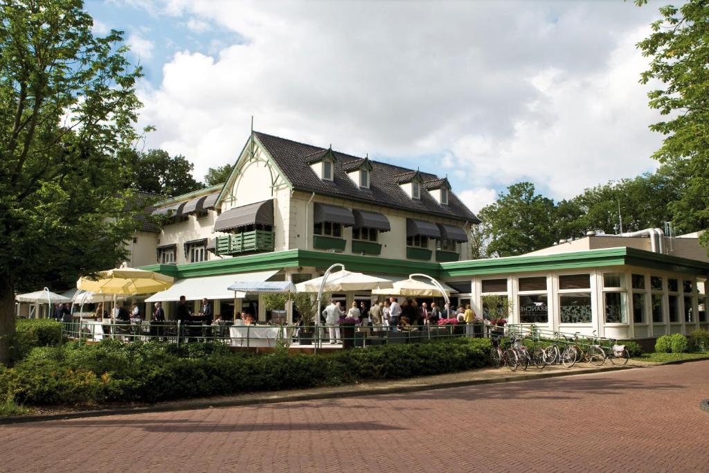 un grand bâtiment avec des personnes debout à l'extérieur dans l'établissement Fletcher Familiehotel Paterswolde, à Eelde-Paterswolde