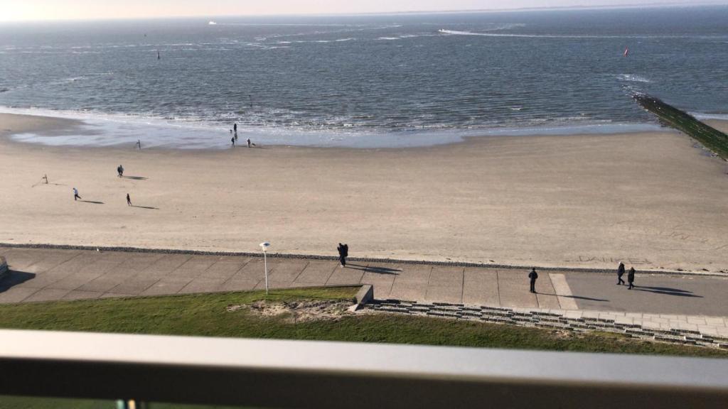 Blick auf einen Strand mit Leuten, die auf dem Sand laufen in der Unterkunft Alte Teestube Appartement 3 Penthouse in Norderney