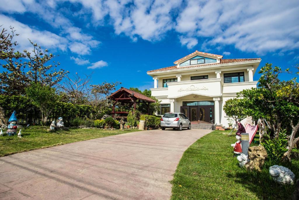a white house with a car parked in the driveway at Sinmanizu Homestay in Hengchun South Gate