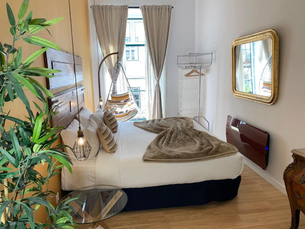 リスボンにあるOld Town Lx Suitesのベッドルーム1室(ベッド1台、鏡、植物付)