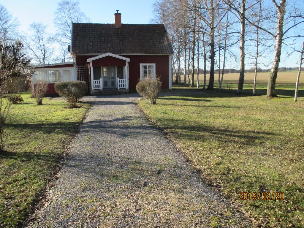 un camino que conduce a una casa roja con entrada en Stuga Olstorp, en Skänninge