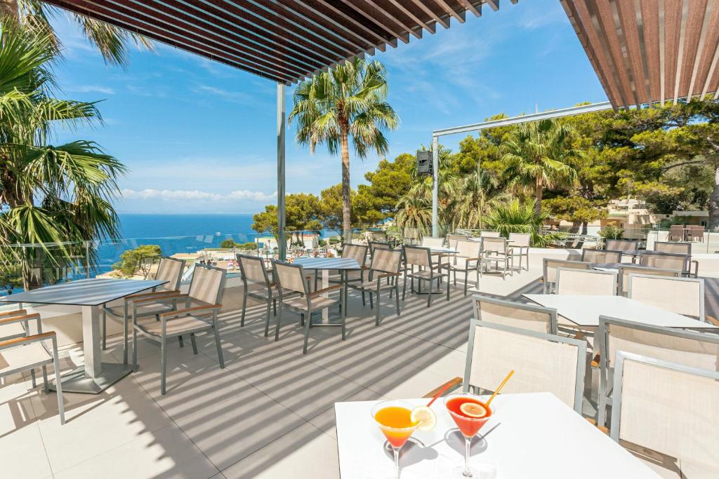 ein Restaurant mit Tischen und Stühlen und das Meer im Hintergrund in der Unterkunft Sun Club El Dorado - All Inclusive in Llucmajor