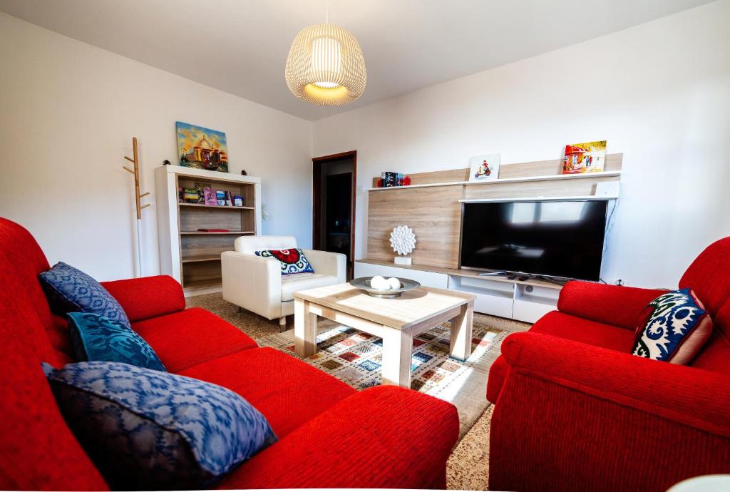 a living room with two red couches and a television at CASA LUJAN in Tijarafe